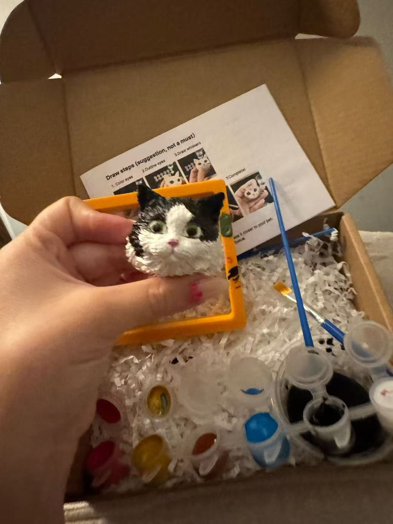 Finished painted 3D cat portrait held above the kit